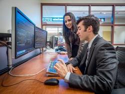 Students from the 费利西亚诺商学院 analyzing stocks on double monitors.